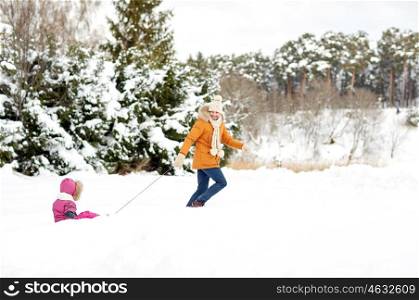 family, sledding, season and people concept - happy father pulling sled with child outdoors in winter