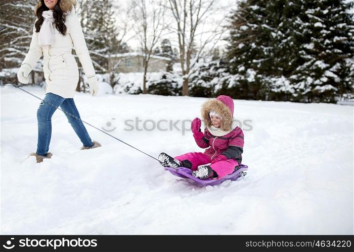 family, sledding, season and people concept - happy mother pulling sled with child outdoors in winter