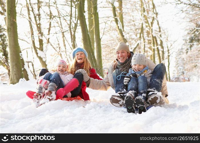 Family Sledging Through Snowy Woodland