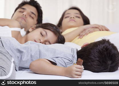 Family sleeping on bed