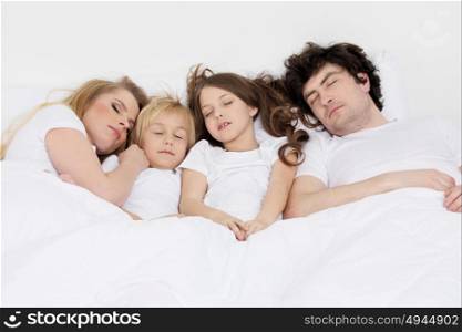 Family sleeping together. Family with two children sleeping together on a same bed