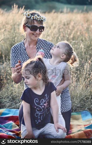 Family spending time together on a meadow, close to nature. Parents and children playing together, making coronet of wild flowers. Candid people, real moments, authentic situations
