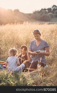 Family spending time together on a meadow, close to nature, parents and children playing together, making coronet of wild flowers. Candid people, real moments, authentic situations