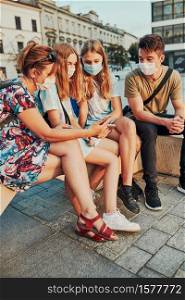 Family spending time together sitting in the city center. Girls wearing the face masks to avoid virus infection and to prevent the spread of disease in time of coronavirus