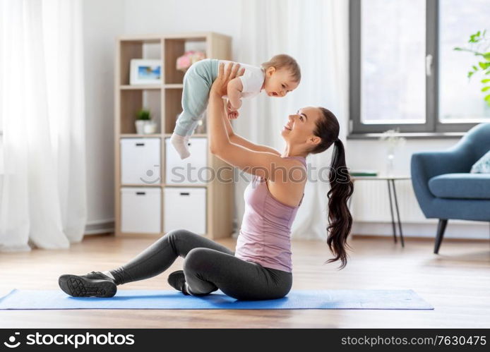 family, sport and motherhood concept - happy smiling mother with little baby exercising at home. happy mother with little baby exercising at home