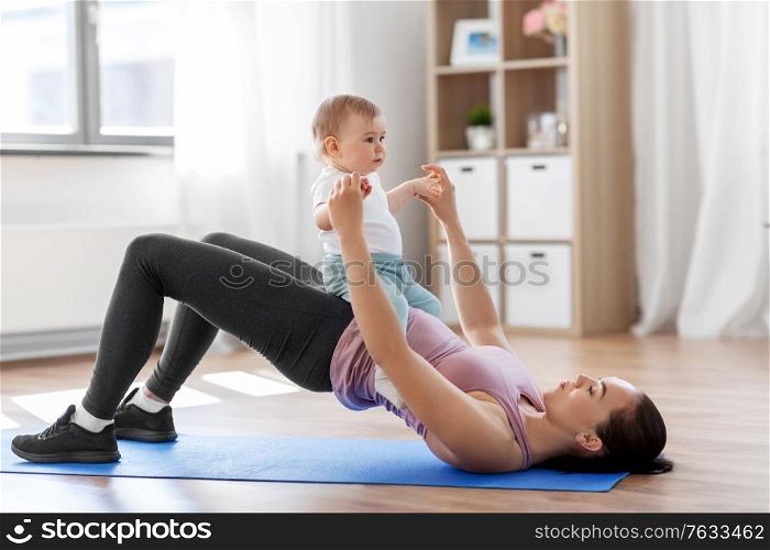 family, sport and motherhood concept - mother with little baby exercising at home. mother with little baby exercising at home