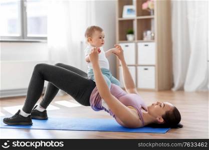 family, sport and motherhood concept - mother with little baby exercising at home. mother with little baby exercising at home