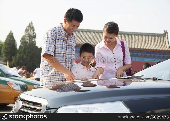 Family standing next to the car and looking at the map