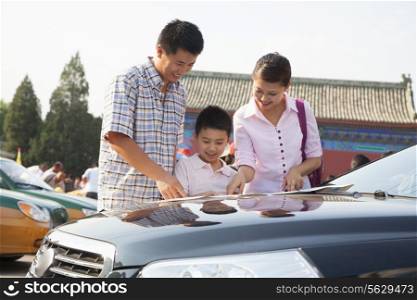 Family standing next to the car and looking at the map