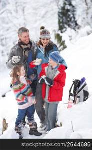 Family Stopping For Hot Drink And Snack On Walk Through Snowy Landscape