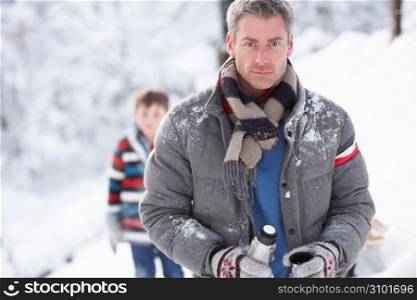 Family Stopping For Hot Drink And Snack On Walk Through Snowy Landscape
