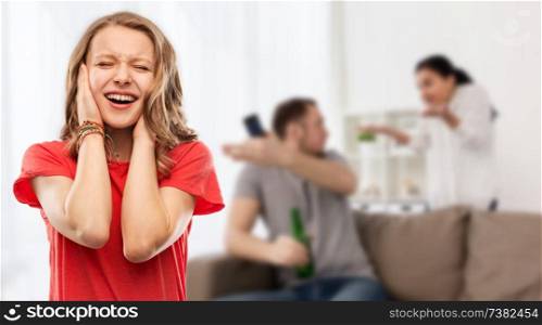 family, stress and social issue concept - unhappy stressed teenage girl covering her ears when her mother and father having fight at home. stressed girl over her parents having fight