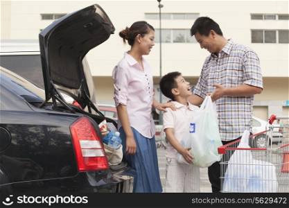 Family talking next to the car with shopping bags