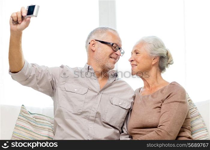 family, technology, age and people concept - happy senior couple taking selfie with camera at home