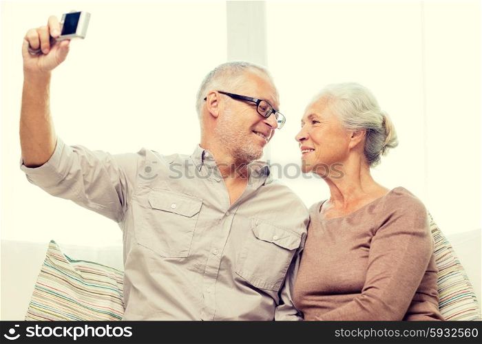 family, technology, age and people concept - happy senior couple taking selfie with camera at home