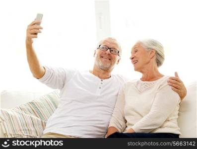 family, technology, age and people concept - happy senior couple with smartphone making selfie at home