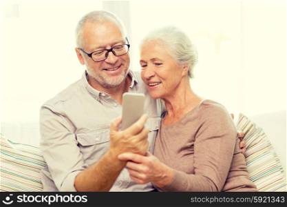 family, technology, age and people concept - happy senior couple with smartphone making selfie at home