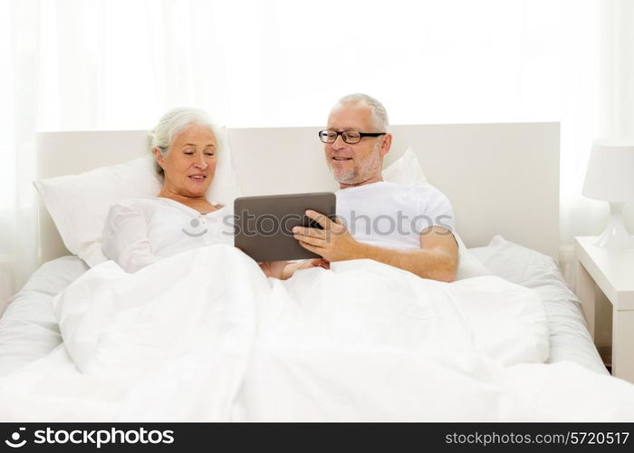 family, technology, age and people concept - happy senior couple with tablet pc computer lying in bad at home