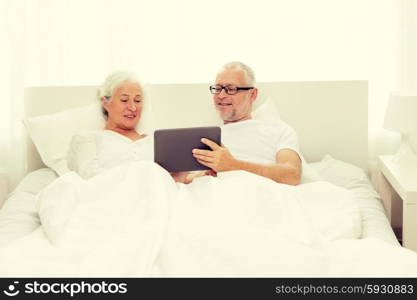 family, technology, age and people concept - happy senior couple with tablet pc computer lying in bad at home