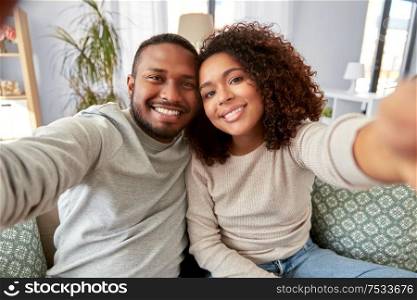 family, technology and people concept - happy african american couple taking selfie at home. african american couple taking selfie at home