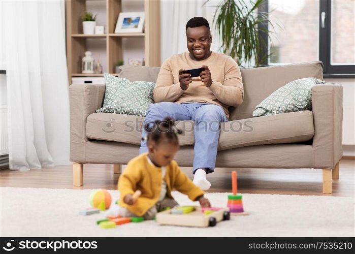 family, technology and people concept - happy african american father with tablet pc computer and baby daughter playing toy blocks at home. happy father with tablet pc and baby at home