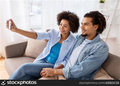 family, technology and people concept - happy couple with smartphone taking selfie at home. happy couple with smartphone taking selfie at home