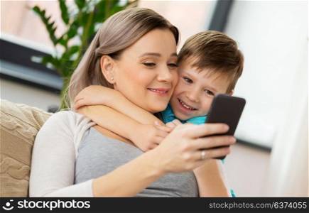 family, technology and people concept - happy mother and little son with smartphone at home. happy family with smartphone at home