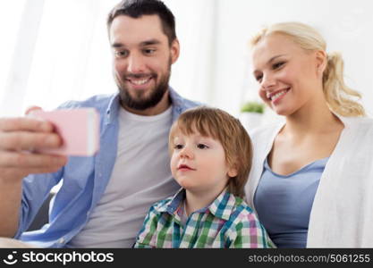 family, technology and people concept - happy mother, father and little boy with smartphone at home. happy family with smartphone at home