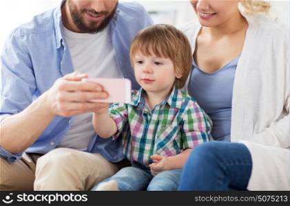 family, technology and people concept - happy mother, father and little boy with smartphone at home. happy family with smartphone at home