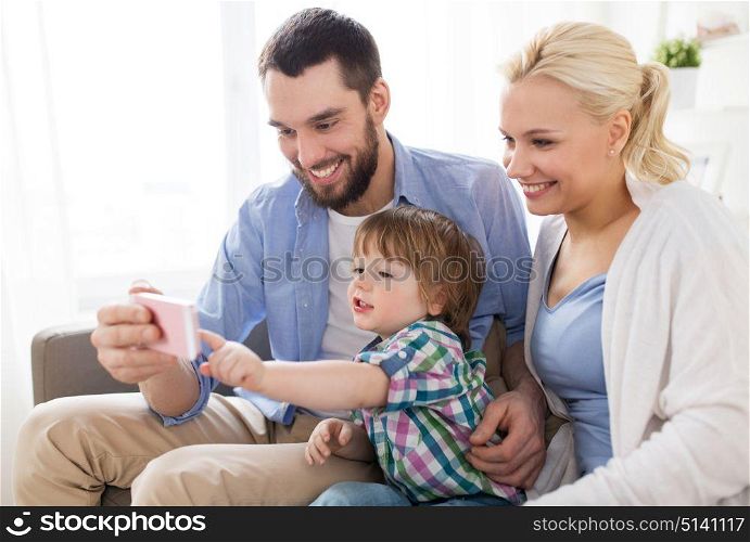 family, technology and people concept - happy mother, father and little boy with smartphone at home. happy family with smartphone at home