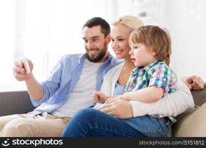 family, technology and people concept - happy mother, father and little boy with smartphone at home. happy family with smartphone at home