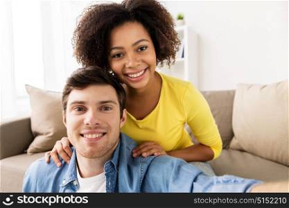family, technology and people concept - happy multiethnic couple taking selfie at home. happy multiethnic couple taking selfie at home