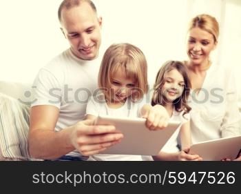 family, technology and people - happy parents and children with tablet pc computers sitting on couch at home