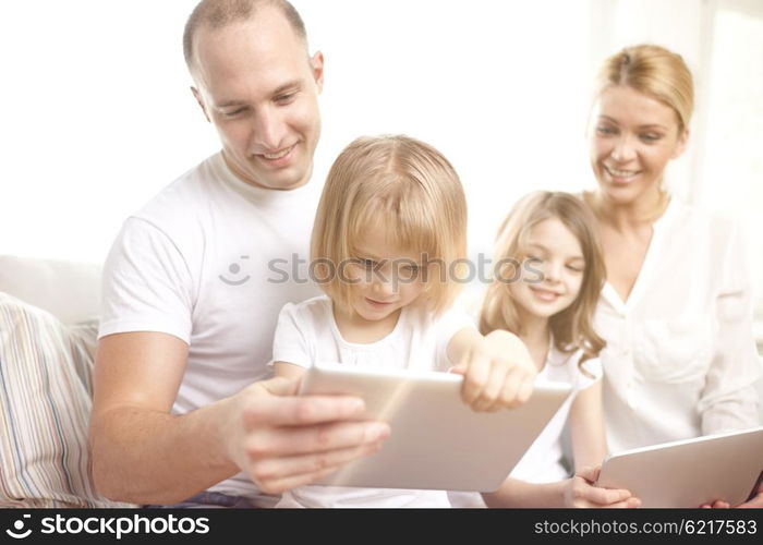 family, technology and people - happy parents and children with tablet pc computers sitting on couch at home