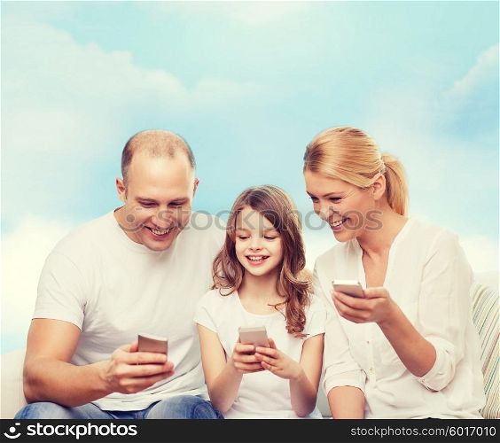 family, technology and people - smiling mother, father and little girl with smartphones over blue sky background