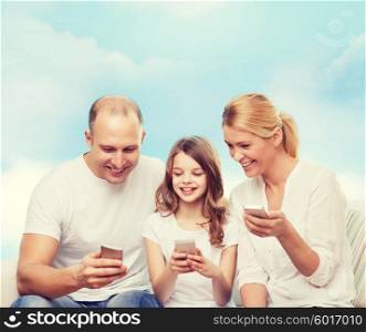 family, technology and people - smiling mother, father and little girl with smartphones over blue sky background