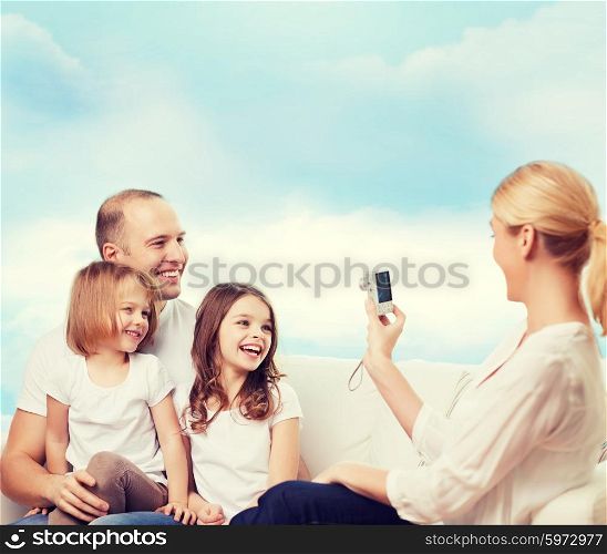 family, technology and people - smiling mother, father and little girls with camera over blue sky background