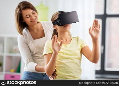 family, technology and virtual reality concept - mother and daughter in vr glasses playing at home. mother and daughter in vr glasses playing at home