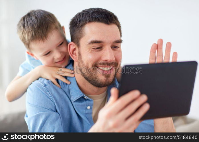 family, technology, communication and people concept - happy father and little son with tablet pc computer having video chat at home. father and son with tablet pc having video chat