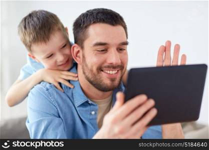 family, technology, communication and people concept - happy father and little son with tablet pc computer having video chat at home. father and son with tablet pc having video chat