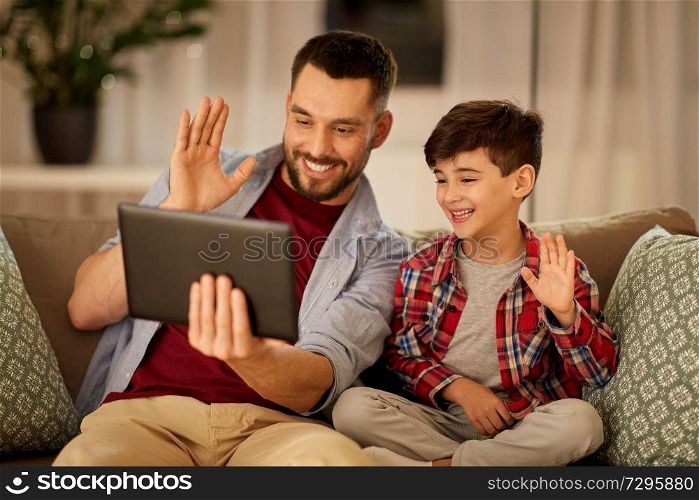 family, technology, communication and people concept - happy father and little son with tablet pc computer having video chat at home. father and son with tablet pc having video chat