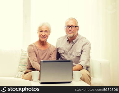 family, technology, drinks, age and people concept - happy senior couple with laptop computer and cups at home