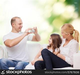 family, technology, ecology and people - smiling mother, father and little girl with camera over green background