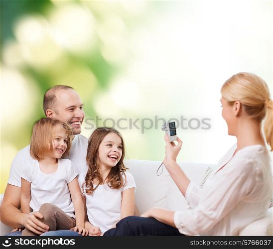 family, technology, ecology and people - smiling mother, father and little girls with camera over green background