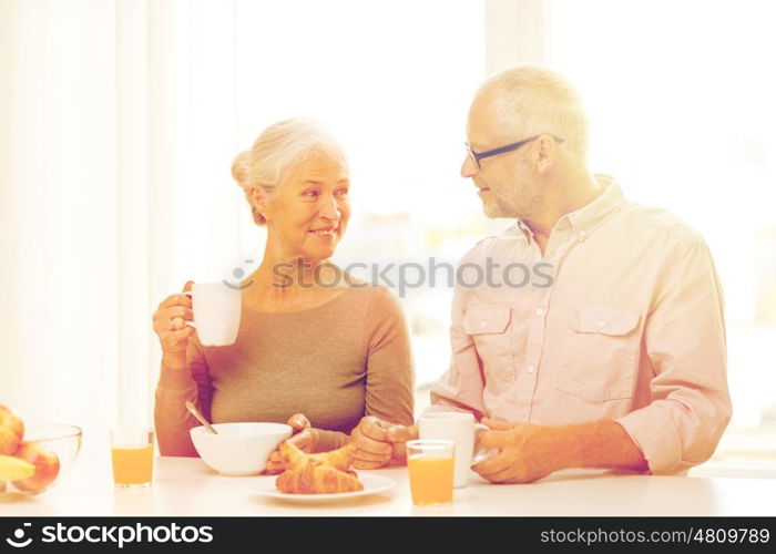 family, technology, food, drinks and people concept - happy senior couple having breakfast at home