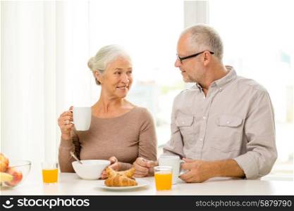 family, technology, food, drinks and people concept - happy senior couple having breakfast at home