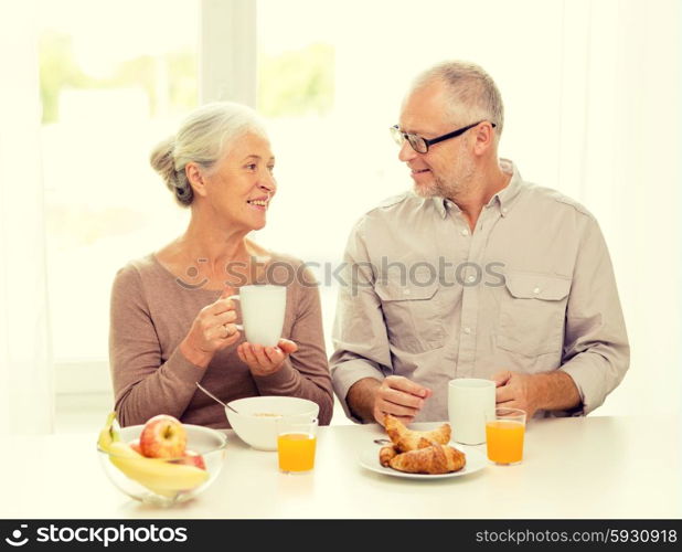 family, technology, food, drinks and people concept - happy senior couple having breakfast at home