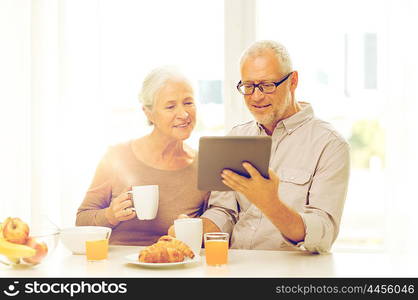 family, technology, food, drinks and people concept - happy senior couple with tablet pc computer having breakfast at home