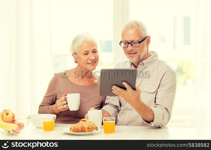 family, technology, food, drinks and people concept - happy senior couple with tablet pc computer having breakfast at home