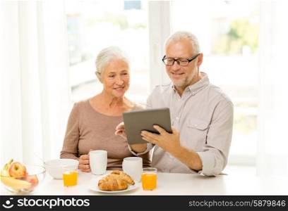 family, technology, food, drinks and people concept - happy senior couple with tablet pc computer having breakfast at home